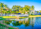 Thumbnail 39 of 42 - A serene lake surrounded by lush greenery and palm trees under a clear blue sky.