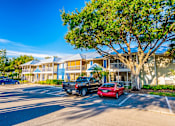 Thumbnail 41 of 42 - A red car is parked in front of a blue and white building.
