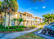 Thumbnail 42 of 42 - A motorcycle is parked on the sidewalk in front of a two-story building with a balcony.