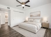 Thumbnail 31 of 42 - A bedroom with a large bed, a ceiling fan, and a painting on the wall.