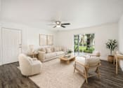 Thumbnail 24 of 42 - A living room with a white couch, a chair, a table, and a ceiling fan.