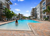 Thumbnail 1 of 59 - A woman is sitting in a pool surrounded by buildings.