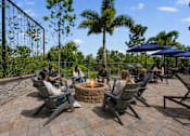 Thumbnail 20 of 59 - A group of people are sitting around a fire pit on a patio.