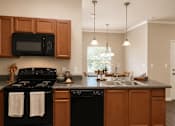 Thumbnail 24 of 37 - A kitchen with black appliances and wooden cabinets.