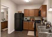 Thumbnail 23 of 37 - A kitchen with a black refrigerator and wooden cabinets.
