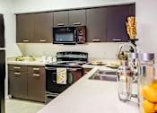 Thumbnail 30 of 33 - A kitchen with a black stove top oven and a black microwave.
