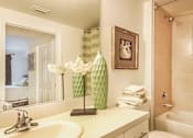 Thumbnail 31 of 33 - A bathroom with a white sink and a green vase.