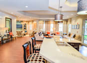 Thumbnail 8 of 33 - A modern kitchen with a long white island and brown chairs.