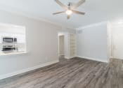 Thumbnail 11 of 30 - an empty living room with a ceiling fan and a kitchen