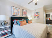 Thumbnail 19 of 30 - A bedroom with a bed, a nightstand with a lamp, and two framed pictures on the wall.