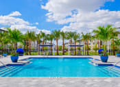 Thumbnail 17 of 23 - a large swimming pool with palm trees and buildings in the background