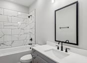 Thumbnail 7 of 38 - A bathroom with a marble tile wall and a white sink.