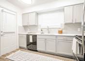 Thumbnail 6 of 20 - a white kitchen with white cabinets and a stainless steel refrigerator