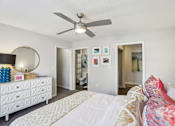 Thumbnail 25 of 31 - A bedroom with a white bed and a white dresser with a mirror.
