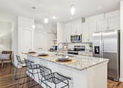 Thumbnail 12 of 34 - A kitchen with a white countertop and stainless steel appliances.