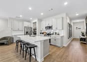 Thumbnail 23 of 37 - A kitchen with white cabinets and a white island with three black stools.