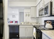 Thumbnail 11 of 40 - A black refrigerator is on the left of a kitchen with a black oven and a black dishwasher.