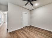 Thumbnail 6 of 20 - A room with a ceiling fan and wooden flooring.