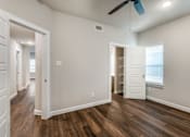 Thumbnail 8 of 20 - A room with a ceiling fan and wooden floors.