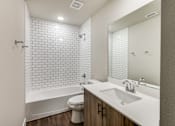 Thumbnail 9 of 20 - A white bathroom with a white toilet, white sink, and white tiles.