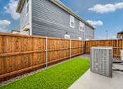 Thumbnail 11 of 20 - A backyard with a wooden fence and a green lawn.