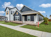 Thumbnail 13 of 20 - A modern house with a grey and black exterior and a red post in the front yard.