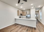 Thumbnail 2 of 20 - A spacious kitchen with wooden floors and white walls.