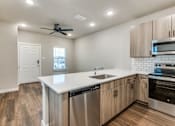 Thumbnail 3 of 20 - A modern kitchen with wooden floors and stainless steel appliances.