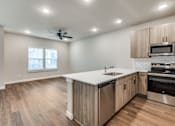 Thumbnail 4 of 20 - A kitchen with wooden floors and stainless steel appliances.