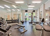 Thumbnail 11 of 21 - A gym with a variety of equipment including weights, machines, and a bench.