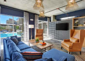 Thumbnail 7 of 17 - a living room with blue couches and a large window with a pool in the background