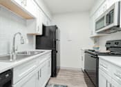 Thumbnail 5 of 17 - A kitchen with black appliances and white cabinets.