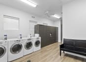 Thumbnail 27 of 32 - a laundry room with washers and dryers and a bench
