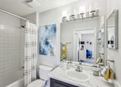 Thumbnail 26 of 31 - A bathroom with a white sink, toilet, and a white tiled shower.