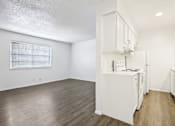 Thumbnail 2 of 21 - A white kitchen with wood floors and white appliances.
