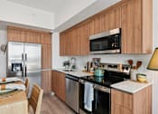 Thumbnail 2 of 26 - A modern kitchen with wooden cabinets and stainless steel appliances.