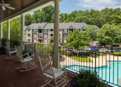 Thumbnail 17 of 17 - a patio with rocking chairs and a pool in front of a building