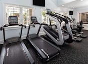 Thumbnail 15 of 25 - A treadmill and a stationary bike are in a well-lit room.
