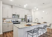 Thumbnail 13 of 34 - A kitchen with a white counter top and black chairs.