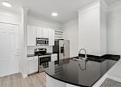 Thumbnail 14 of 42 - A kitchen with white cabinets and a black countertop.