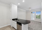 Thumbnail 16 of 42 - A kitchen with white cabinets and a black countertop.