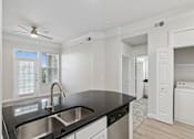 Thumbnail 38 of 42 - A modern kitchen with a black countertop and stainless steel sink.