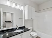 Thumbnail 19 of 42 - A white bathroom with a black counter top and a white toilet.