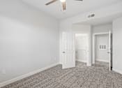 Thumbnail 18 of 42 - A room with a ceiling fan and carpeted floor.