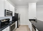Thumbnail 15 of 42 - A kitchen with black countertops and white cabinets.