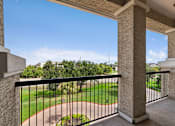 Thumbnail 21 of 42 - A balcony with a black railing and a view of a green lawn and trees.