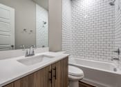 Thumbnail 14 of 15 - A white bathroom with a white tub and a white sink.