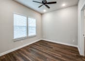 Thumbnail 6 of 15 - A room with a ceiling fan and wooden flooring.