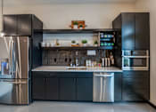 Thumbnail 3 of 15 - A modern kitchen with black cabinets and stainless steel appliances.