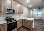 Thumbnail 12 of 15 - A modern kitchen with wooden cabinets and a stainless steel oven.
